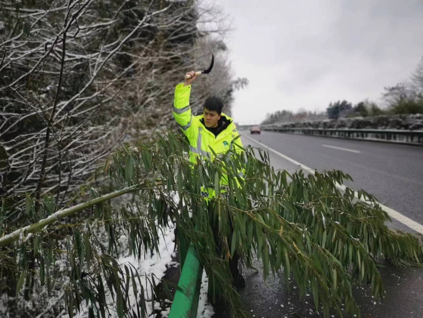 巡檢人員砍伐積雪壓倒在高速公路的樹木